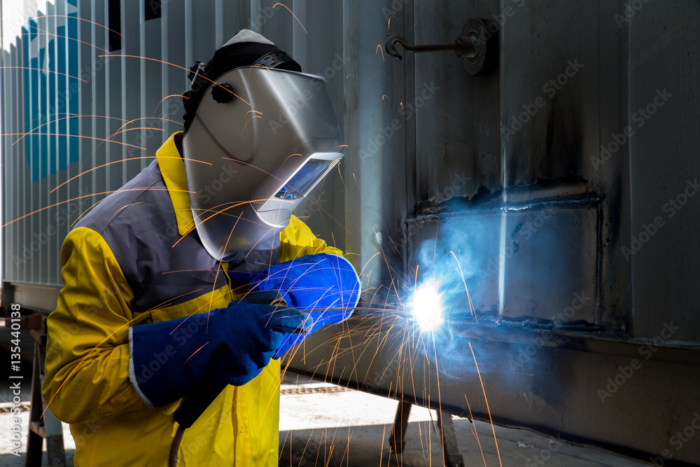 Industry worker with welding steel to repair container structure