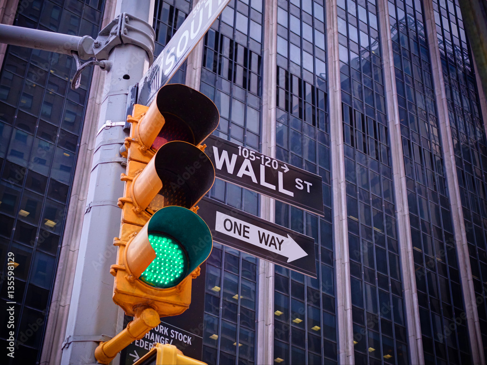 View on Wall street yellow traffic light with black and white Wall street, One way pointer guides. G