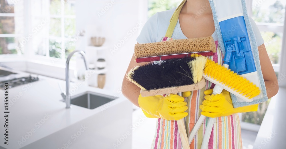 Mid section of female cleaner holding various brushes 