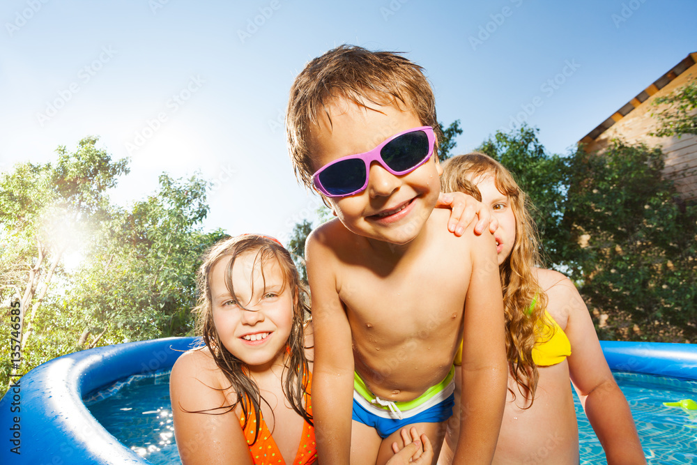 可爱的男孩和两个女孩在游泳池玩得很开心