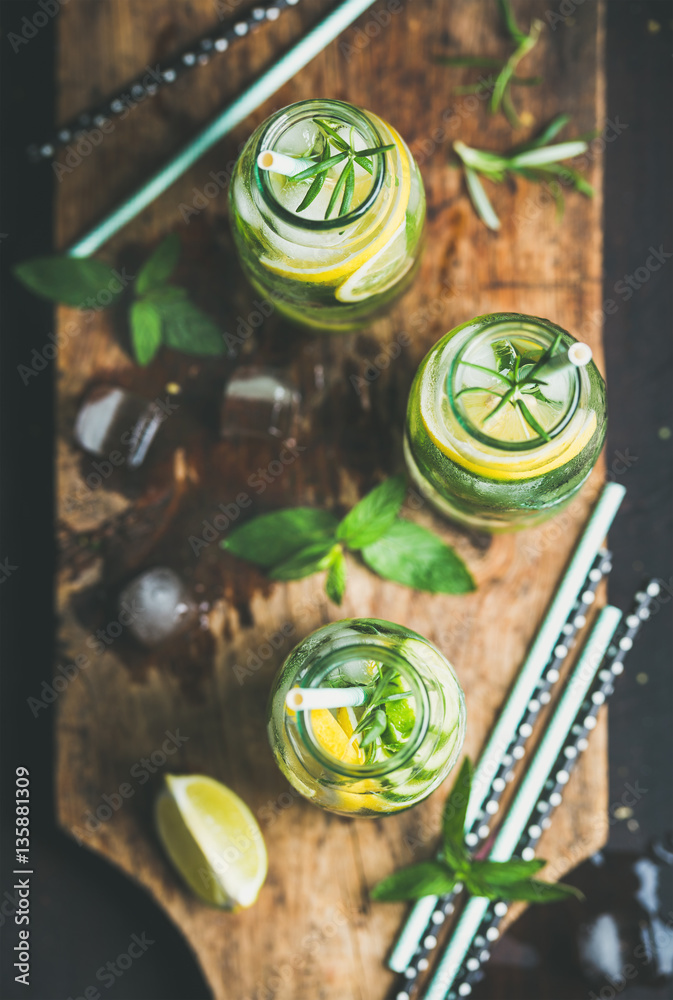 Citrus and herbs infused sassi water for detox, healthy eating, dieting in glass bottles on wooden b