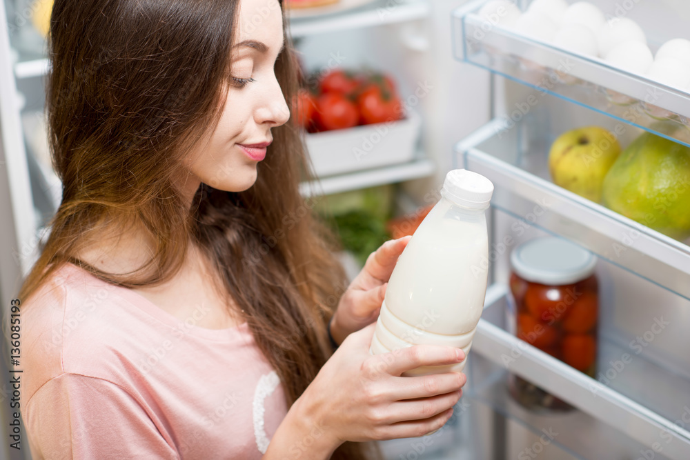 Young woman taking bottle of milk from the refrigerator
