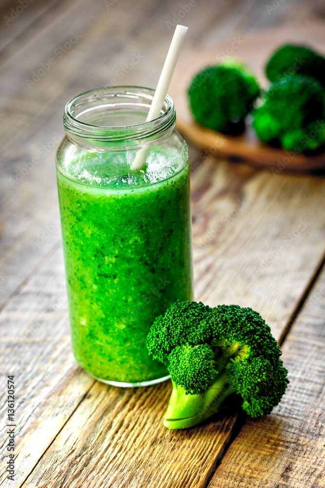 Green vegetable smoothie in glass at wooden background