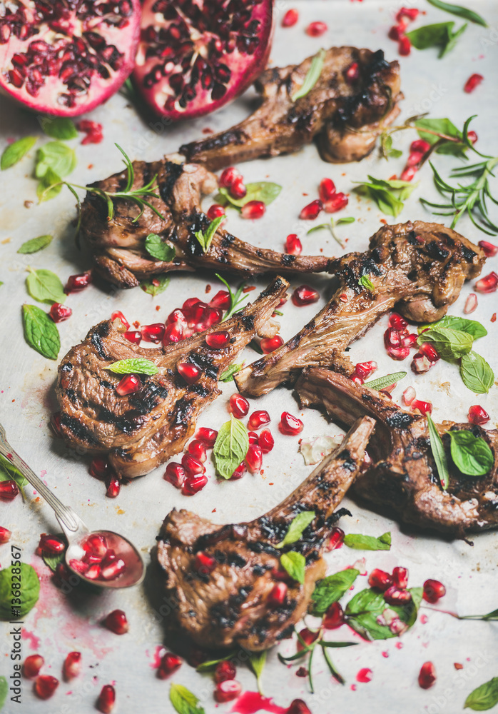 Grilled lamb ribs with pomegranate seeds, fresh mint and rosemary in metal baking tray. Meat barbecu
