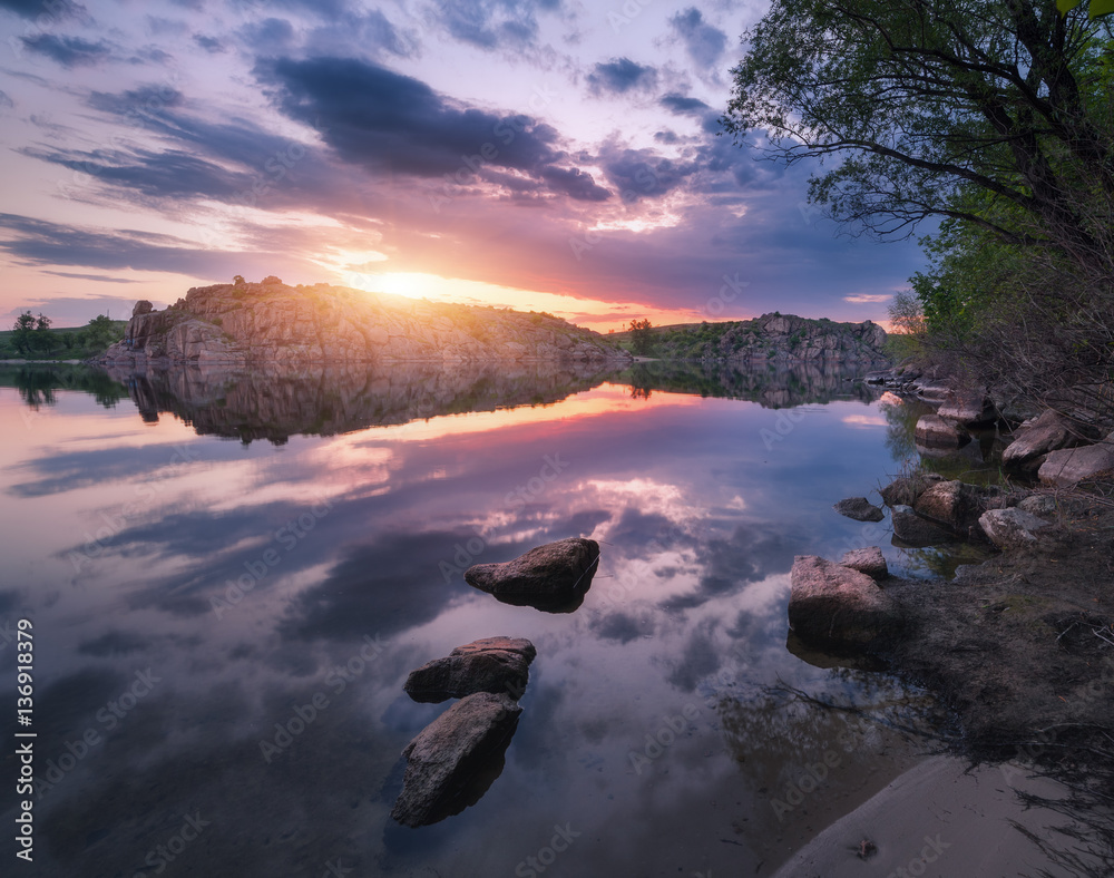 River against colorful sky with clouds and rocks at sunset in summer. Beautiful landscape with lake,