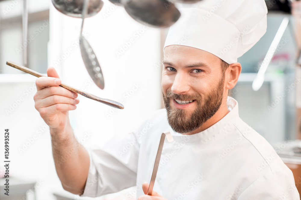 厨师在餐厅厨房用木勺品尝食物