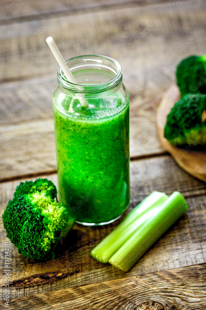 Green vegetable smoothie in glass at wooden background