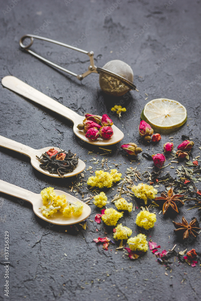 Spoons with herbs on dark stone background