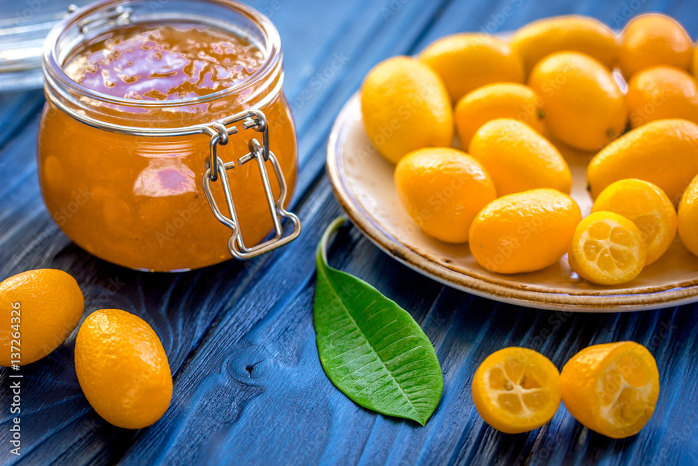 kumquat on plate and jam in jar at wooden table