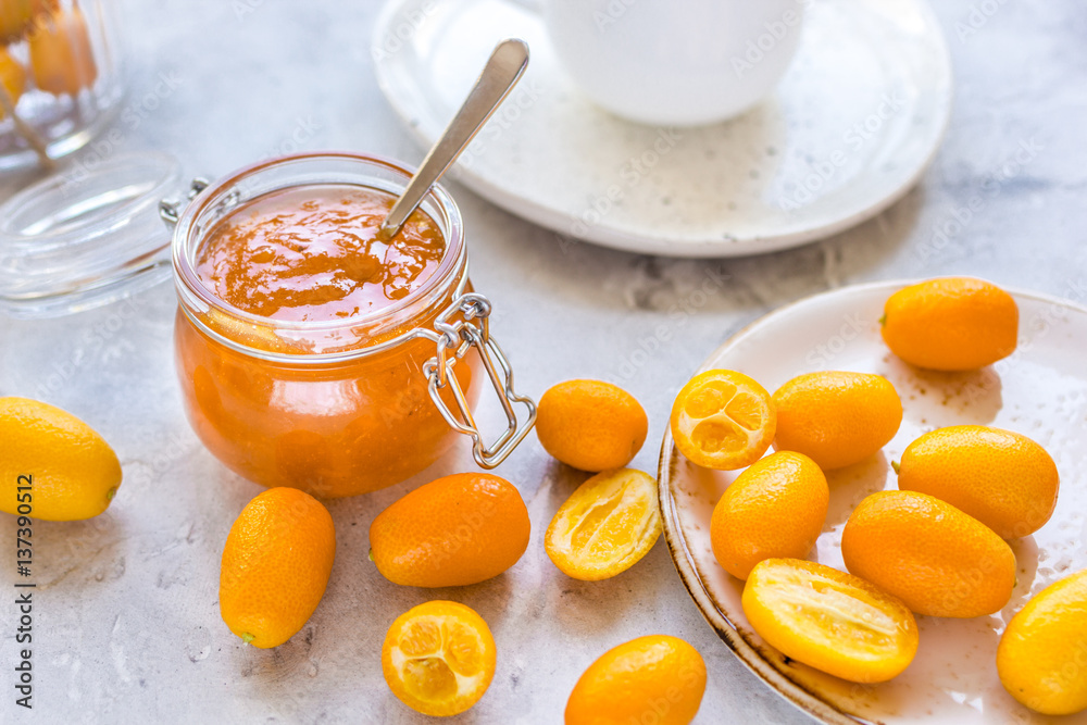 kumquat on plate and jam in jar at gray background
