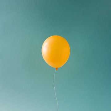 Yellow balloonon blue sky. Minimal concept.
