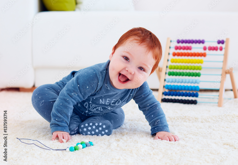 delighted happy infant baby playing on carpet at home