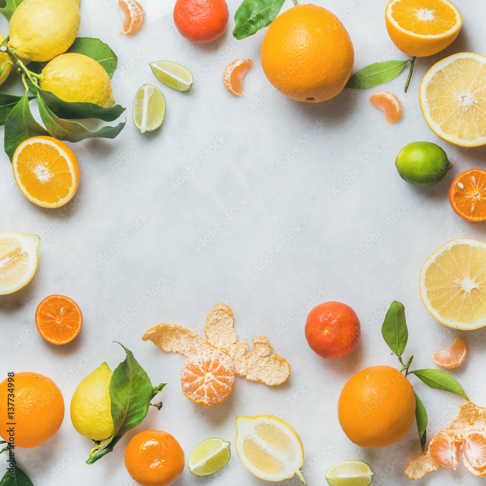 Variety of fresh citrus fruit for making juice or smoothie over light grey marble table background, 