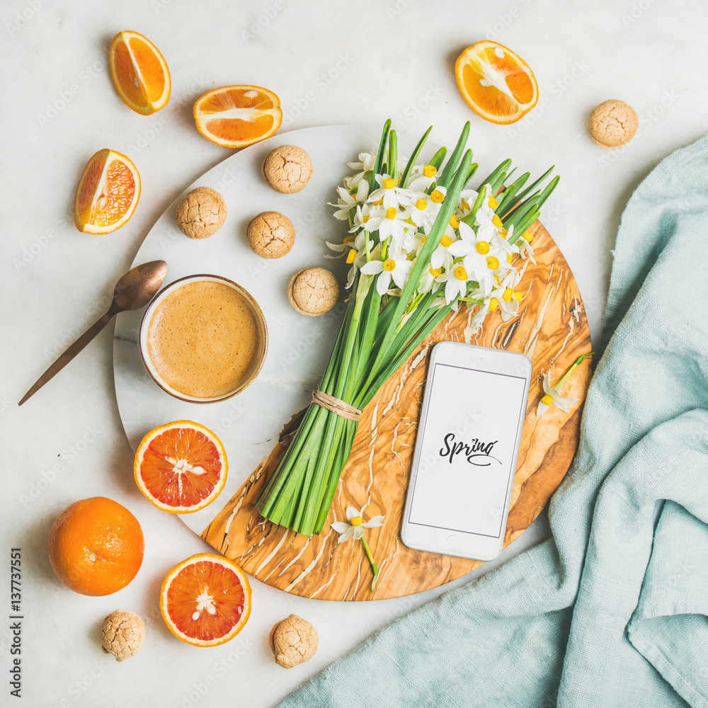 Cup of morning coffee, cookies, red oranges, flowers and mobile phone with text Spring on serving bo