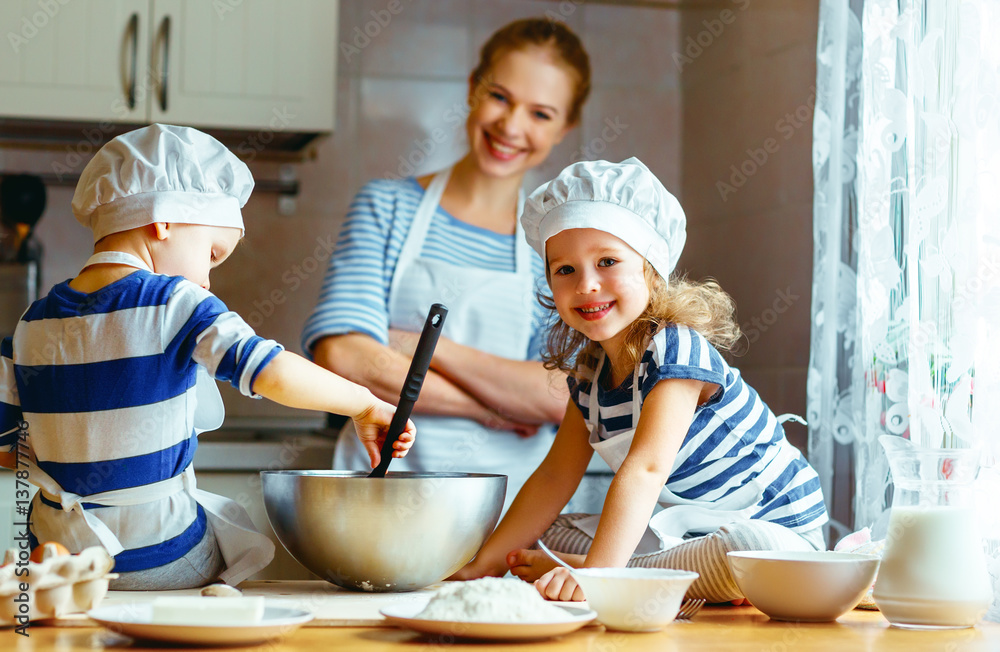 happy family in kitchen. mother and children preparing dough, bake cookies