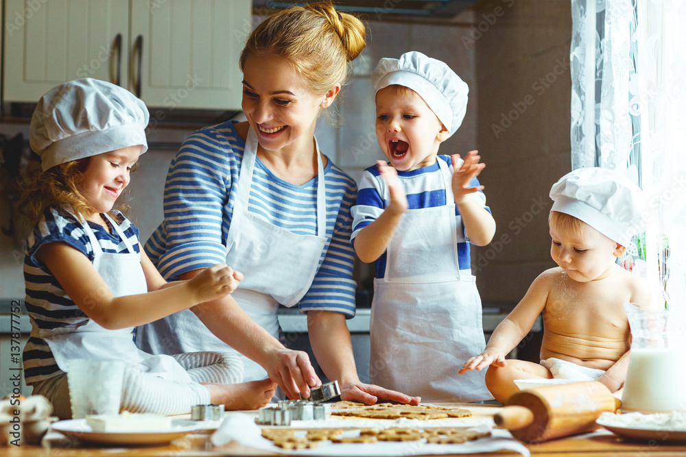 厨房里的幸福家庭。母亲和孩子们准备面团，烤饼干。