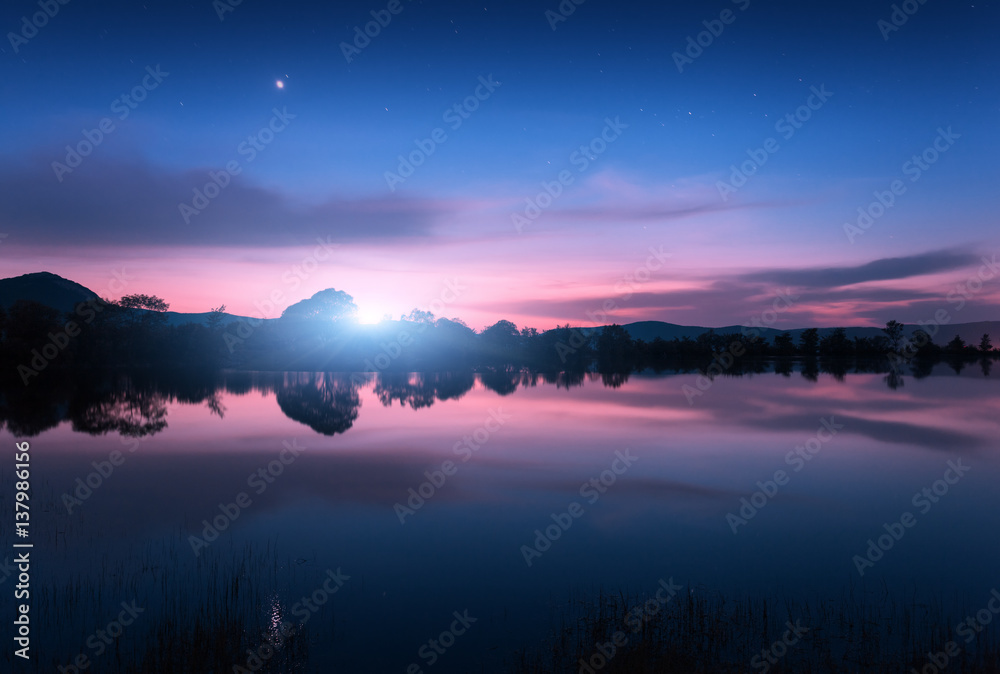 夜晚月出的山湖。河流、树木、山丘、月亮和五颜六色的夜晚景观