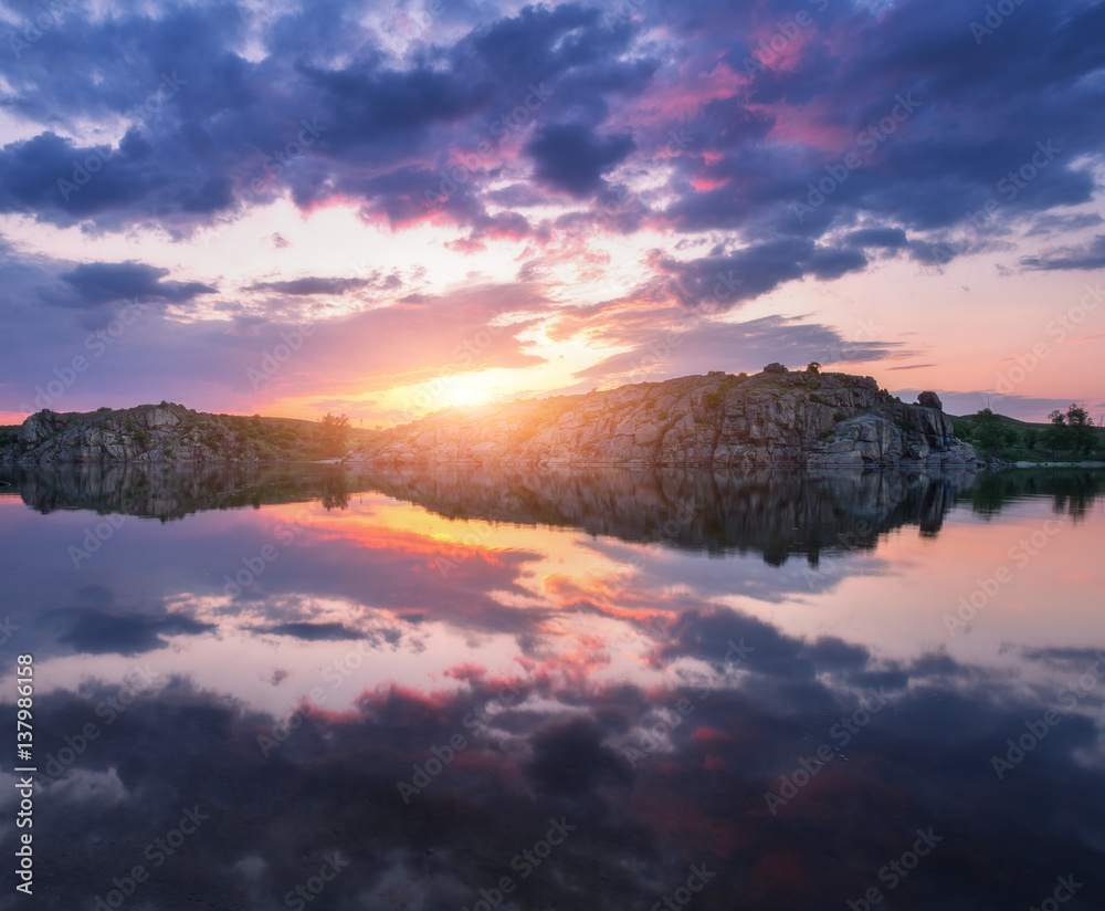 River against colorful sky with clouds and rocks at sunset in summer. Beautiful landscape with lake,