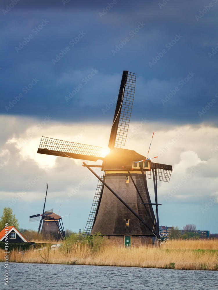 Windmills against cloudy sky at sunset in famous Kinderdijk, Netherlands. Rustic landscape with dutc