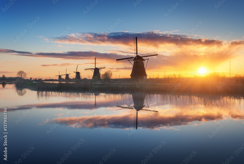 Silhouette of windmills at amazing foggy sunrise in Kinderdijk, Netherlands. Rustic landscape with d