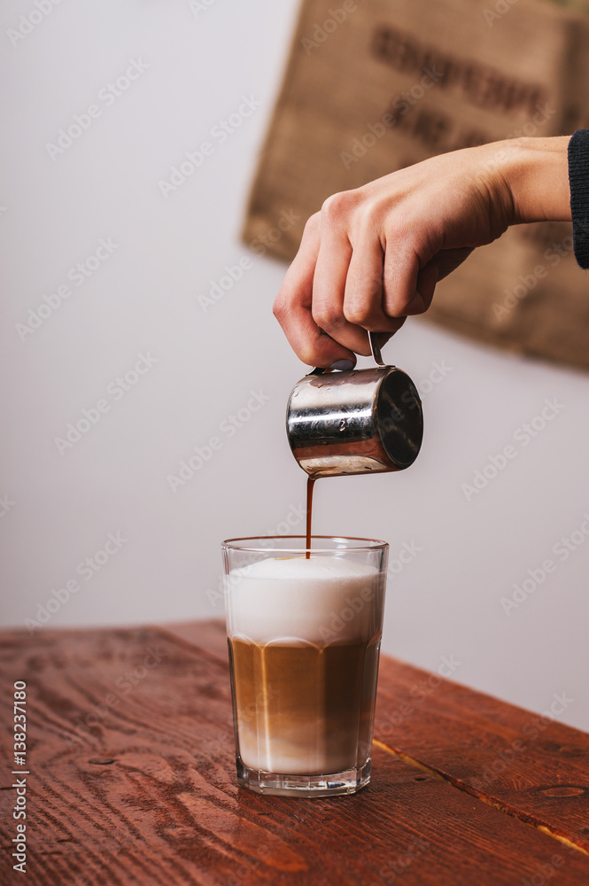 咖啡师在咖啡馆的卡布奇诺咖啡中倒牛奶