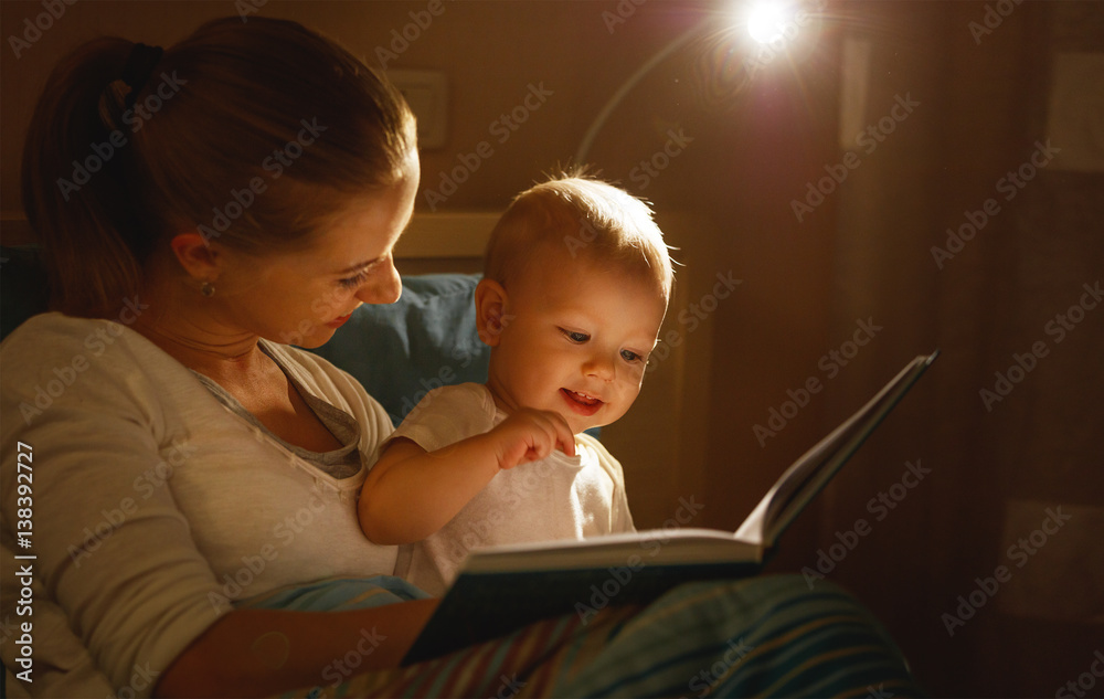 mother reads to baby book in bed