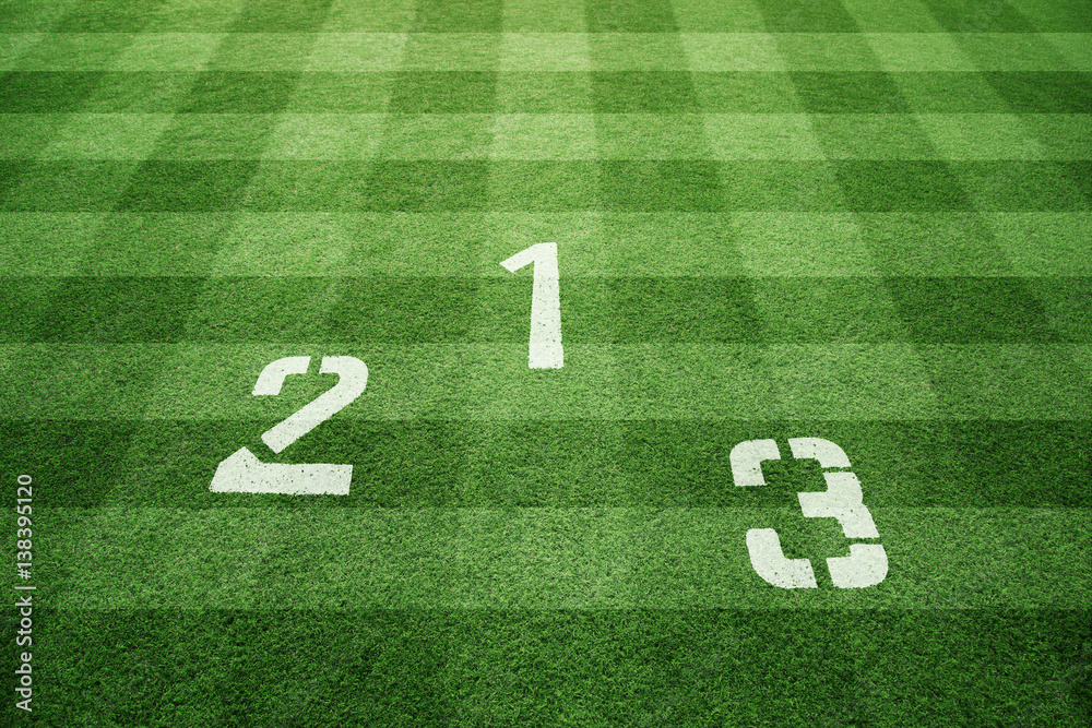 Conceptual winners podium with first, second and third place numbers on green soccer or football fie