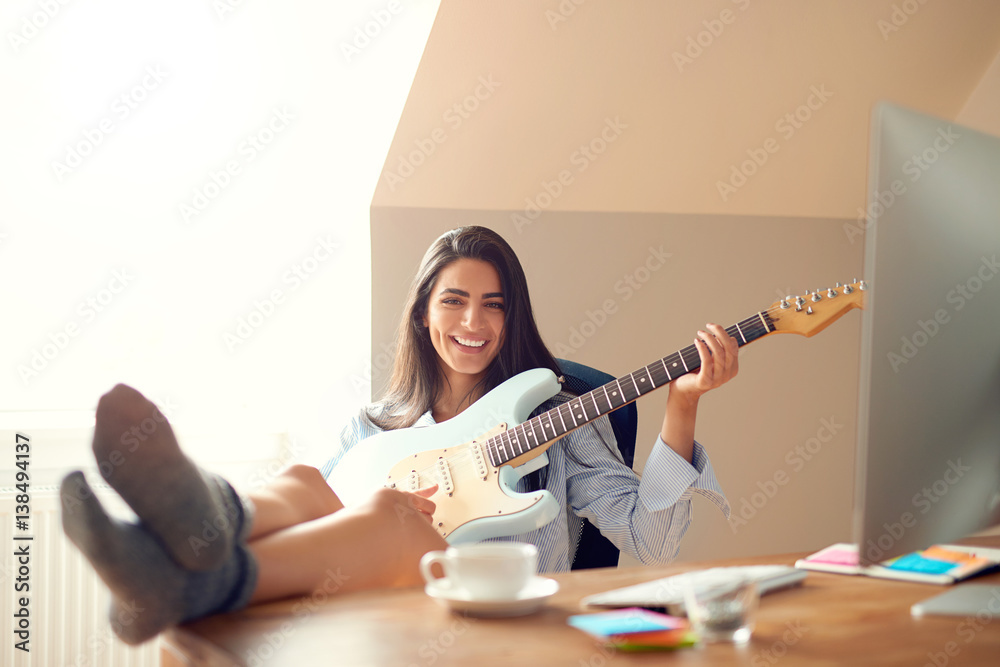Cute young woman with guitar and feet on table