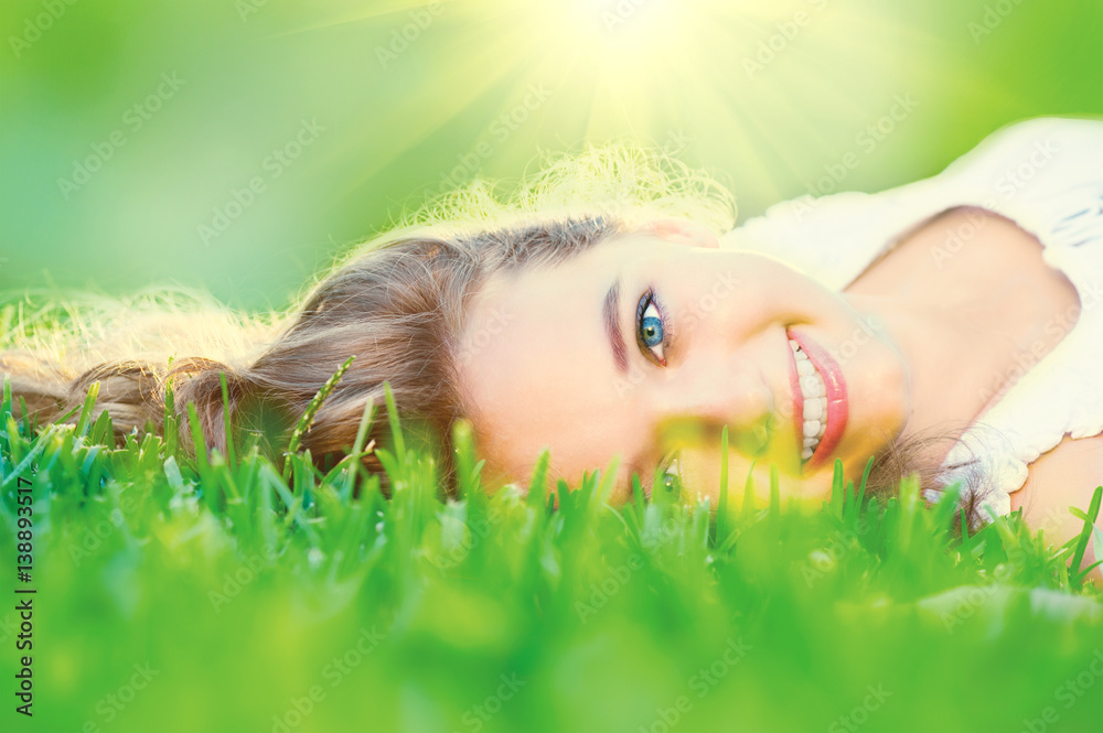 Beautiful teenage girl lying on green grass outdoor
