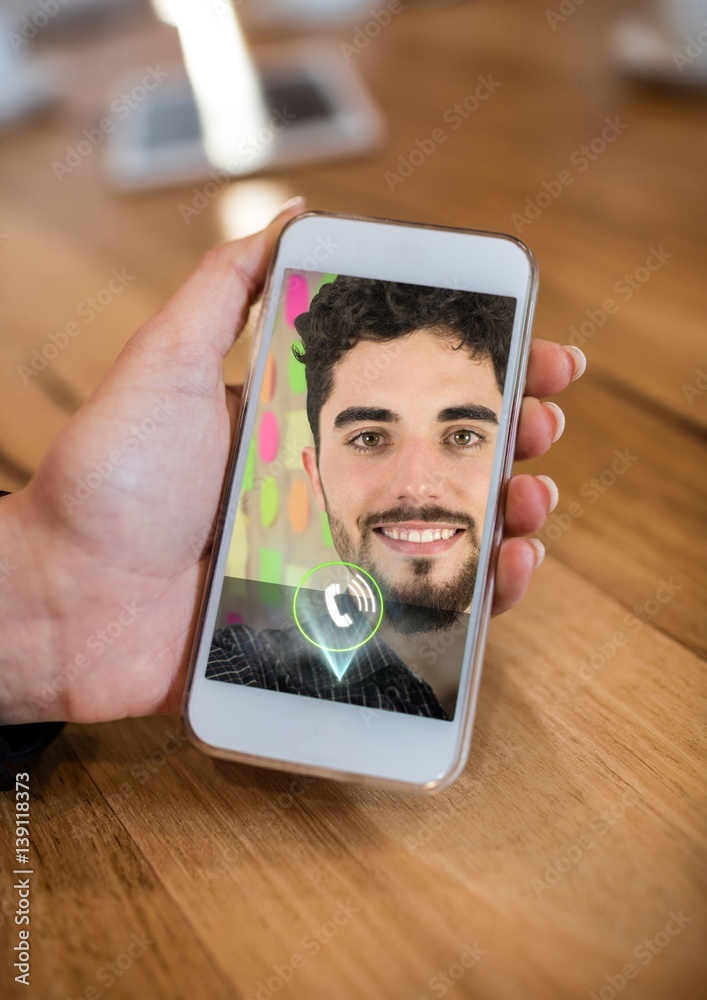 Hand holding mobile phone displaying man on video call screen