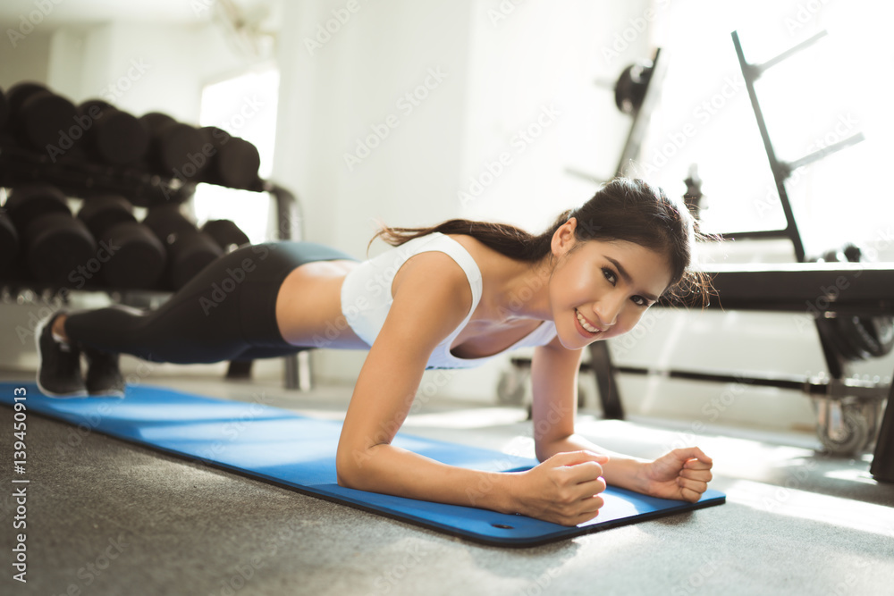 亚洲女性在健身房锻炼，她假装要做平板运动