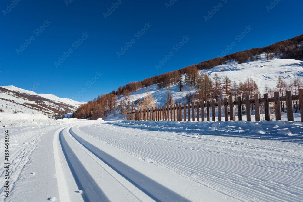 Snowcapped road to alpine resort with ski tracks