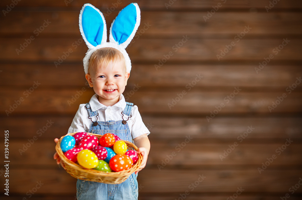 Happy baby boy in Easter bunny suit with basket of eggs