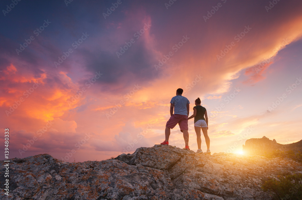 Silhouette of happy people on the mountain against colorful sky at sunset. Landscape with silhouette