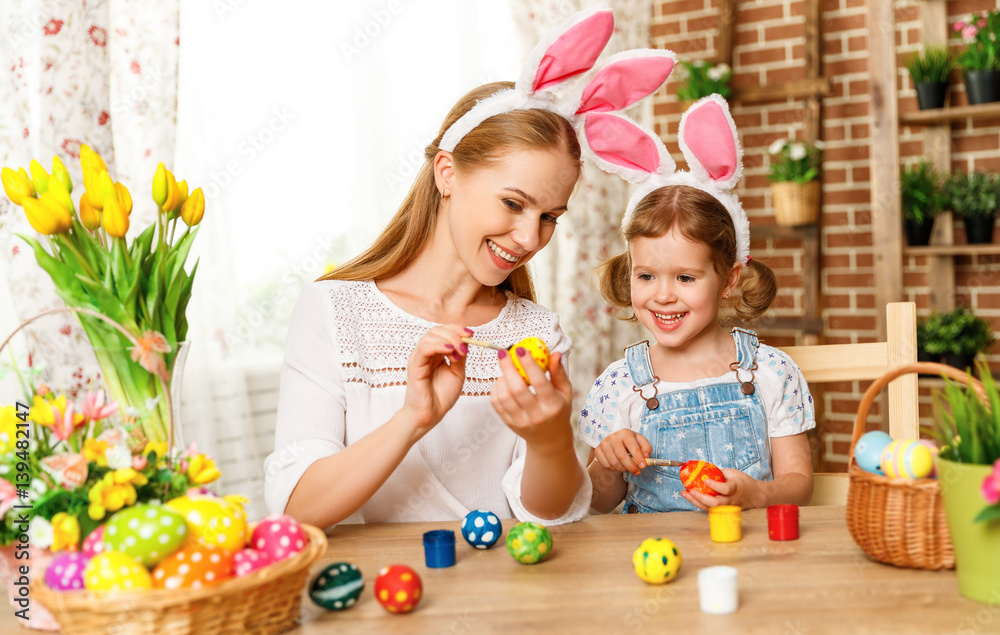 Happy easter! family mother and child daughter paint eggs for holiday Easter