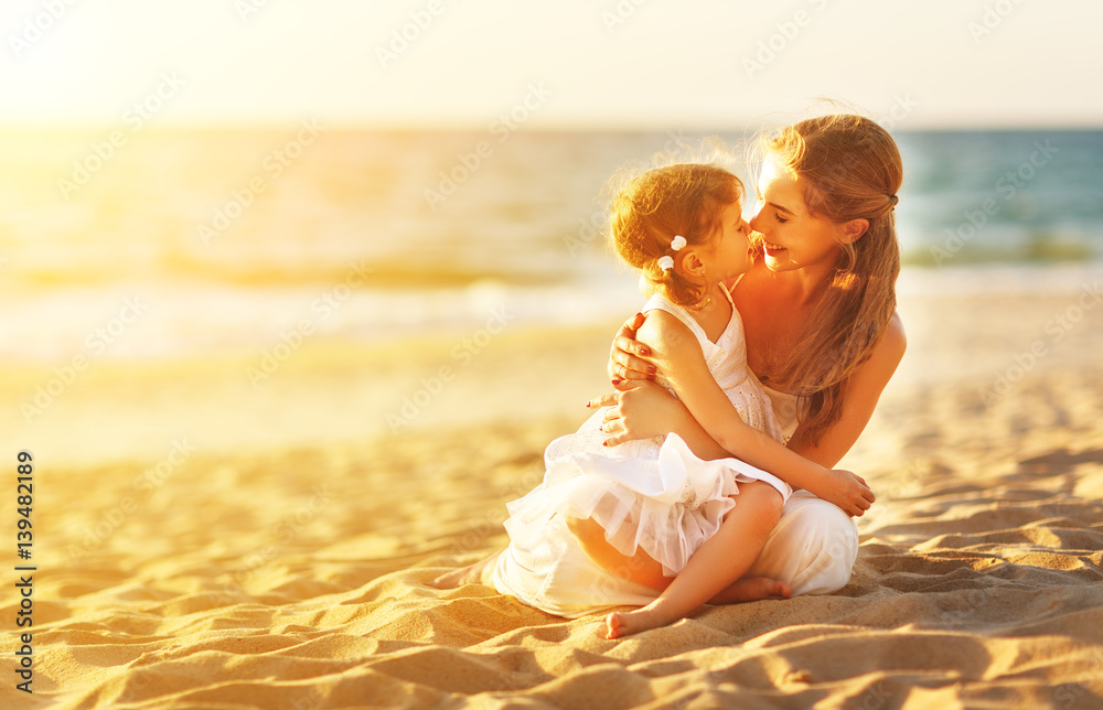 happy family at beach. mother hugging baby daughter at sunset