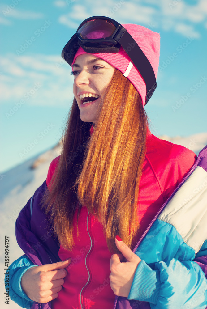 Happy girl removes ski jacket , standing on top of a snow mountain