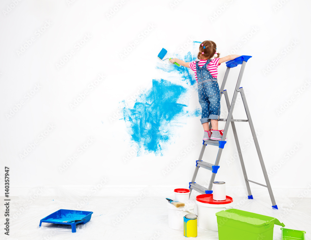 公寓维修。快乐的小女孩粉刷墙壁