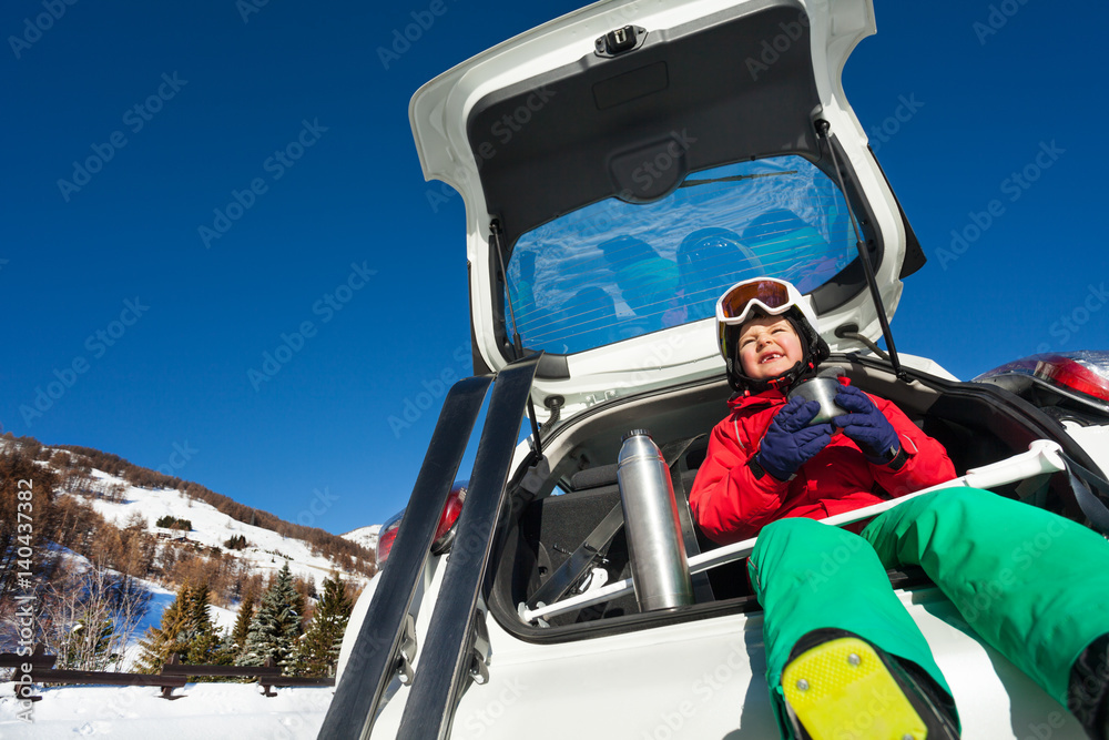 滑雪运动员坐在汽车后备箱里喝热茶