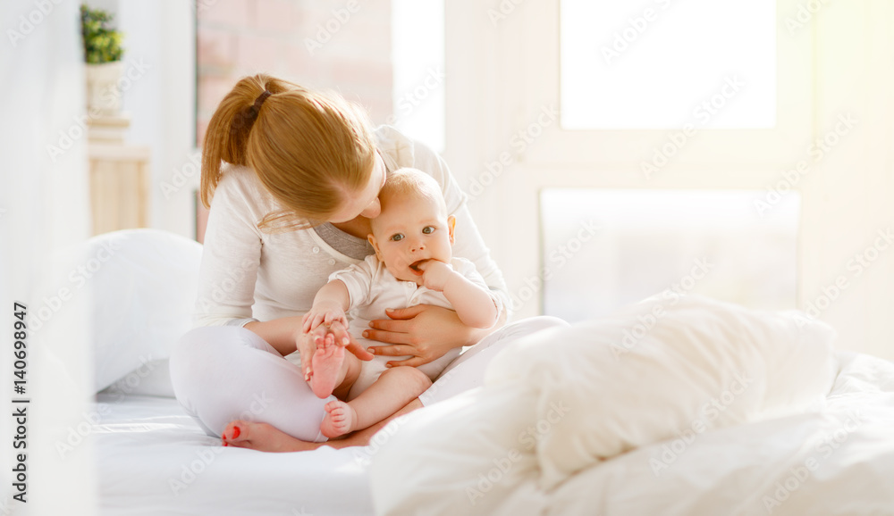 快乐的家庭母亲和婴儿在床上玩耍、拥抱
