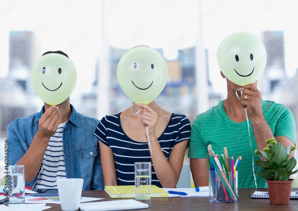 Executives sitting at desk with smiley faces on their face 