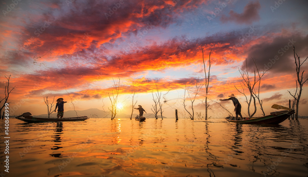 渔民在船上用网捕鱼，日落背景