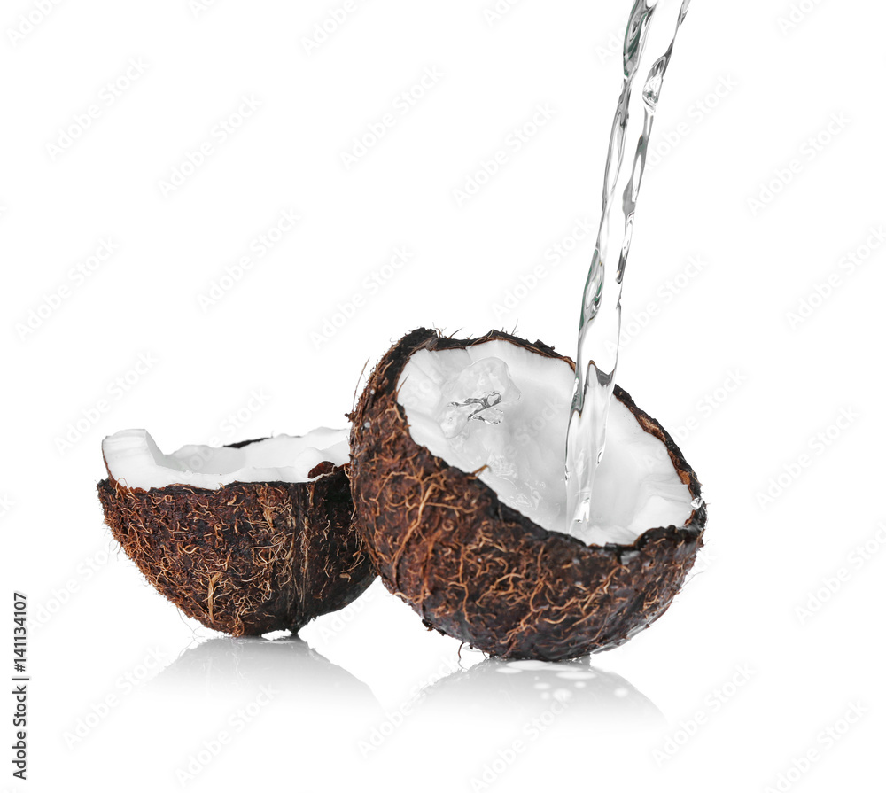Cracked coconut with jet of water on white background