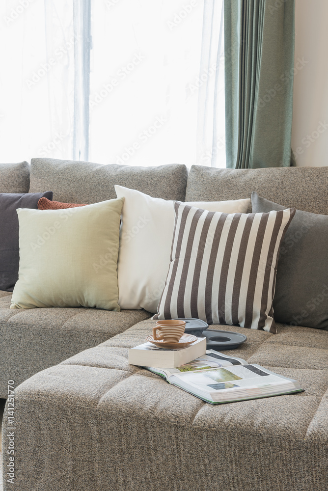 cup of tea on book with modern sofa and set of pillows in modern living room