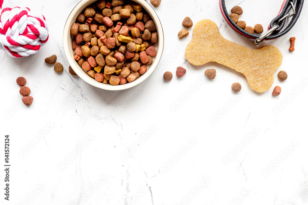 dry dog food in bowl on stone background top view