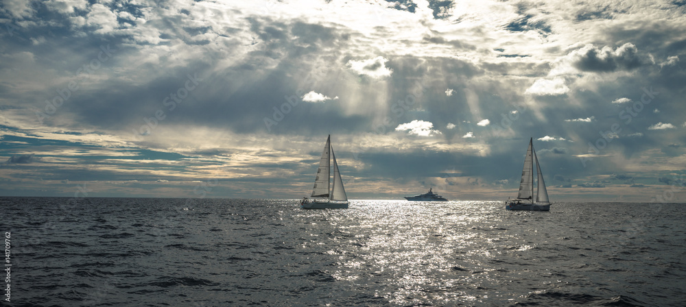 海上赛舟会游艇，阳光透过乌云照亮
