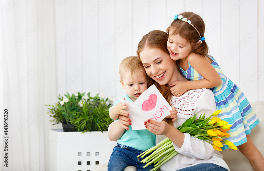 Happy mothers day! Children congratulates moms and gives her a postcard and flowers