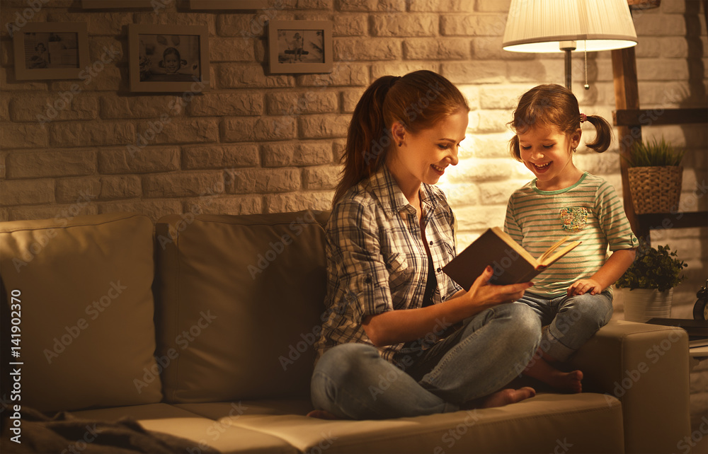 家人睡前，母亲晚上在灯旁给孩子女儿读书