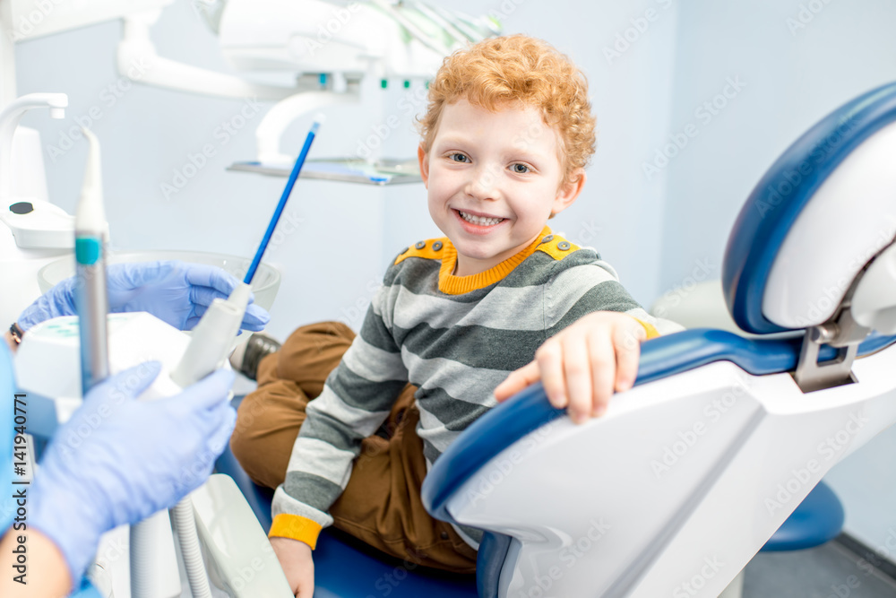 一个快乐的小男孩坐在牙科诊所的牙科椅上，笑容满面