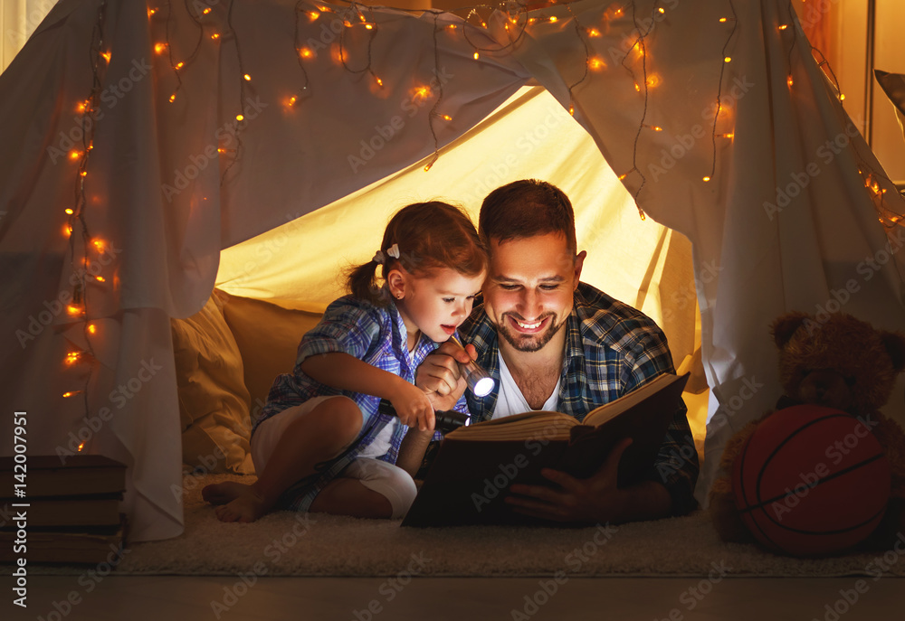 幸福的家庭父亲和小女儿在家里的帐篷里看书。